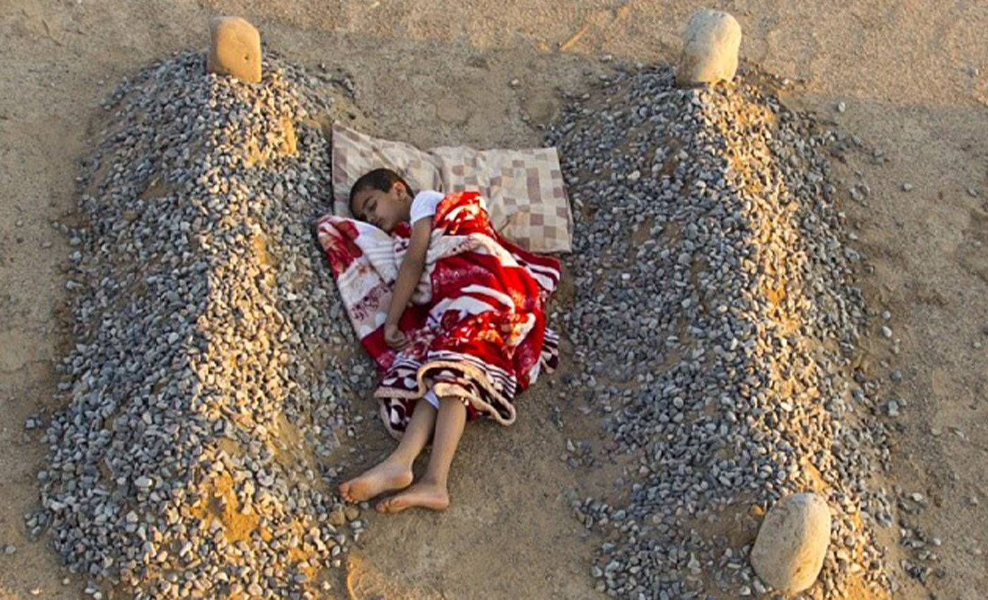 A widely shared image shows a Syrian boy sleeping between his parents' graves.