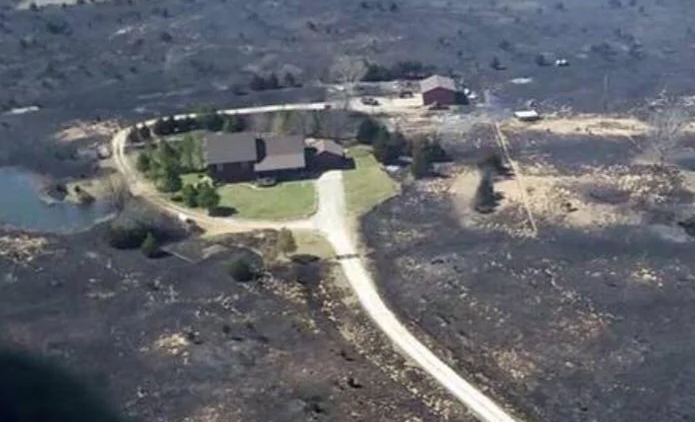 This image shows a house that was saved from a forest fire because the owner left the sprinklers running before evacuating.